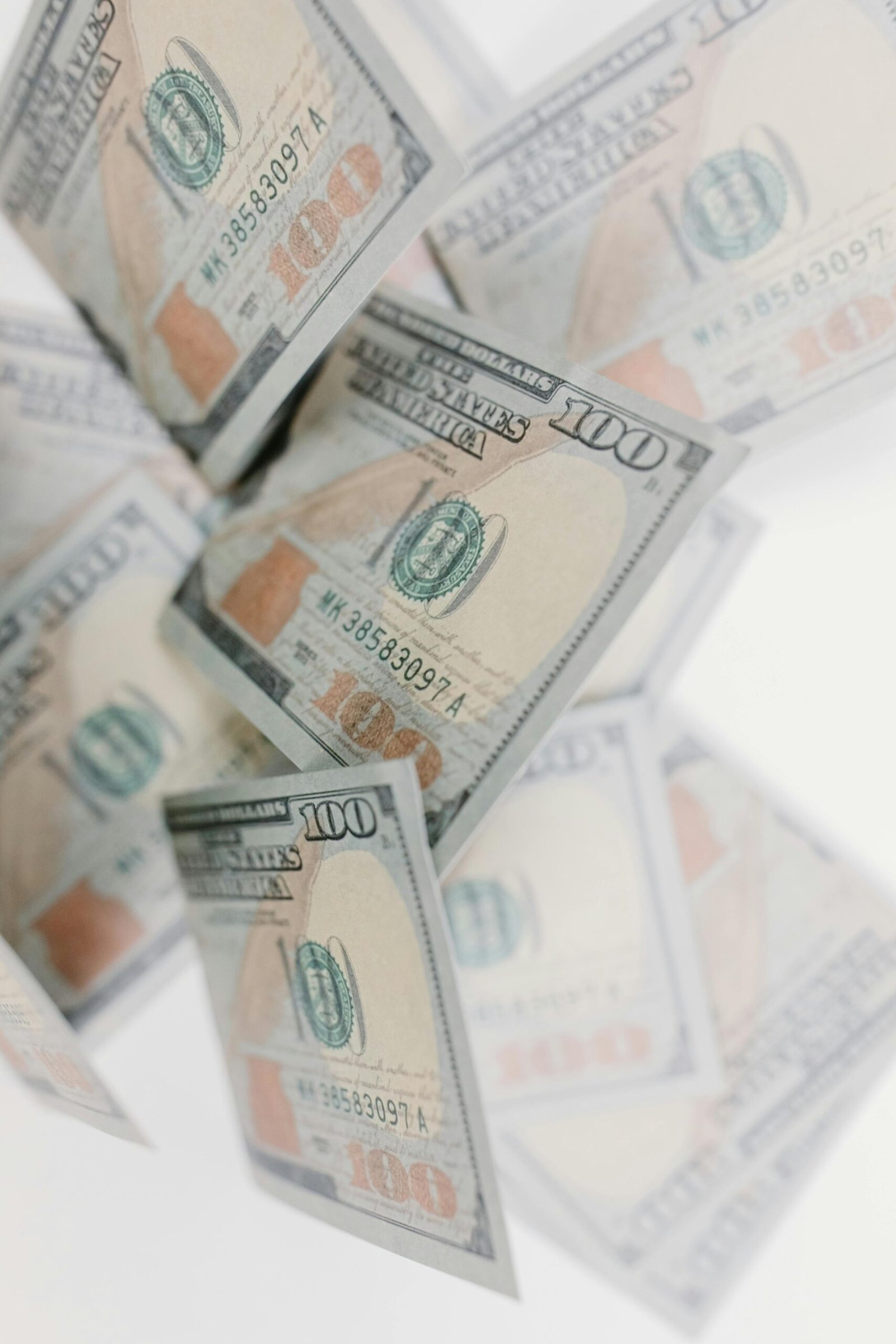 A collection of 100 dollar bills floating against a white background, emphasizing wealth and finance.